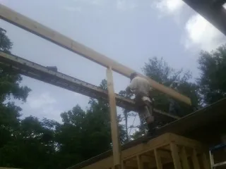 Carpenter setting a ridge beam over a new addition frame — Ice Dam Removal by Roofing Brothers in Tussy