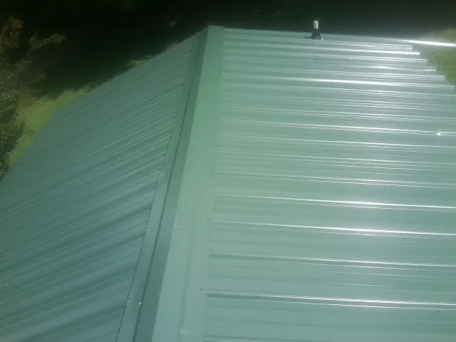 New green metal panels meeting at the ridge of a roof — Flat Roof Repair work by our crew in Tussy