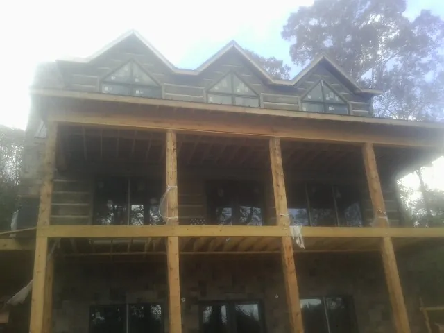 Dormers and porch framing on a large log home under construction — Roof Coating work by our crew in Tussy
