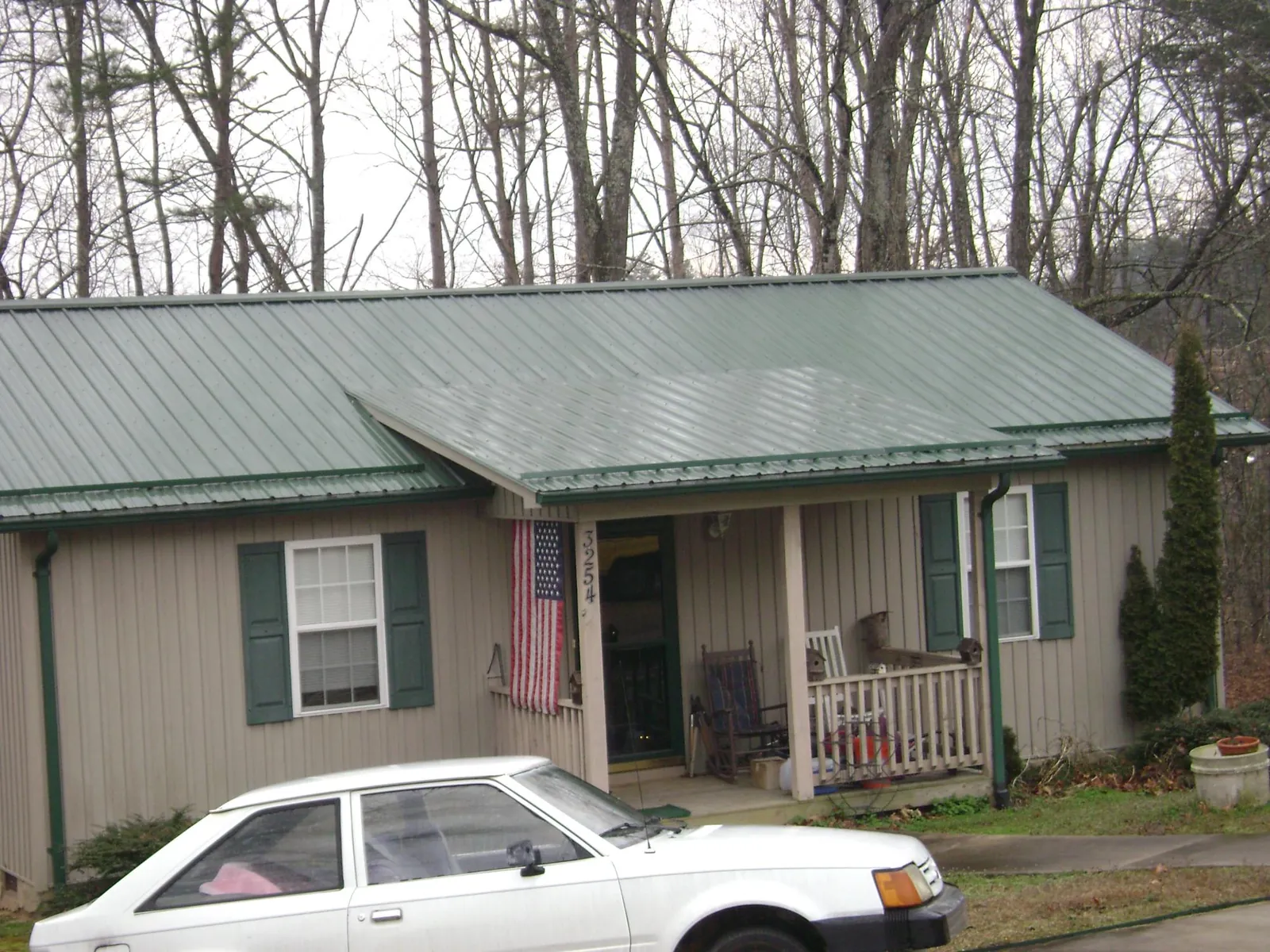 Green metal roof and front porch on a tan sided cottage in Tussy