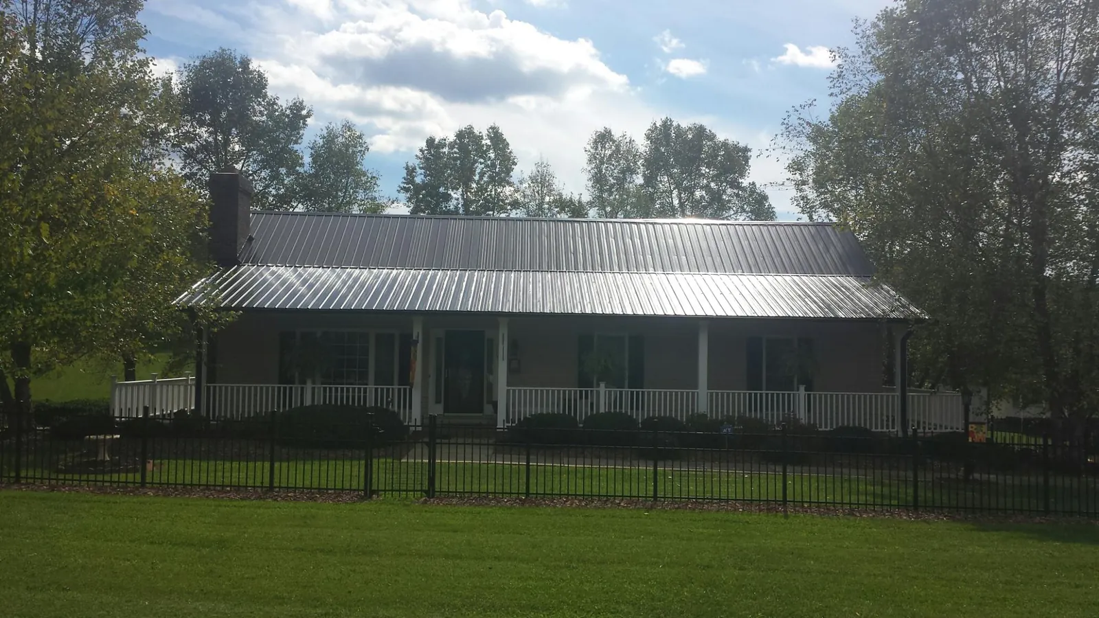 Gray metal roof on a brick ranch with a full width front porch — Gutter Guard Installation work by our crew in Tussy