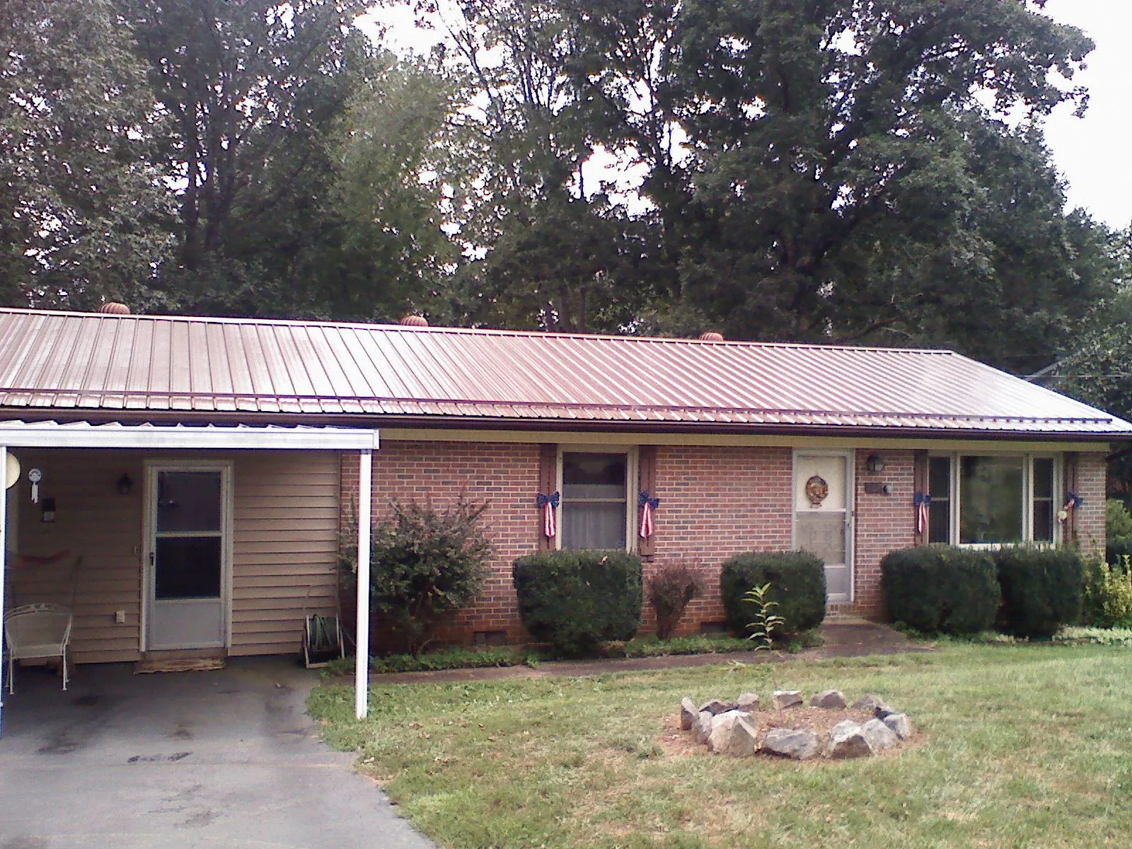 Bronze metal roof and carport on a brick ranch home — Roof Repair work by our crew in Tussy