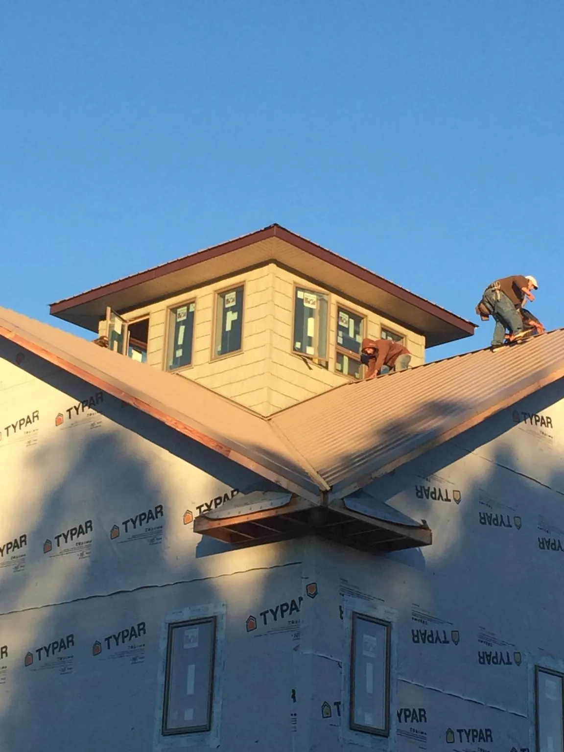 Roofers working around a rooftop cupola on a new metal roof at sunset — Roof Waterproofing in Tussy by Roofing Brothers